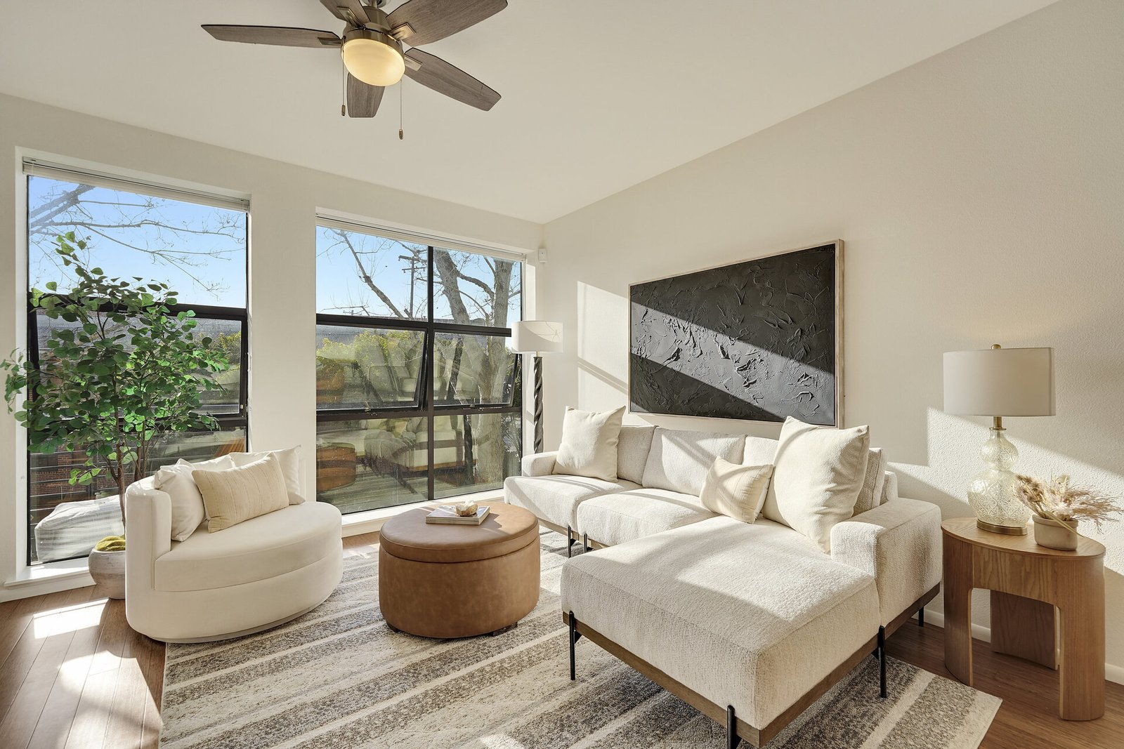 Detailed view of the living room with a white sofa, leather ottoman, and a ceiling fan.