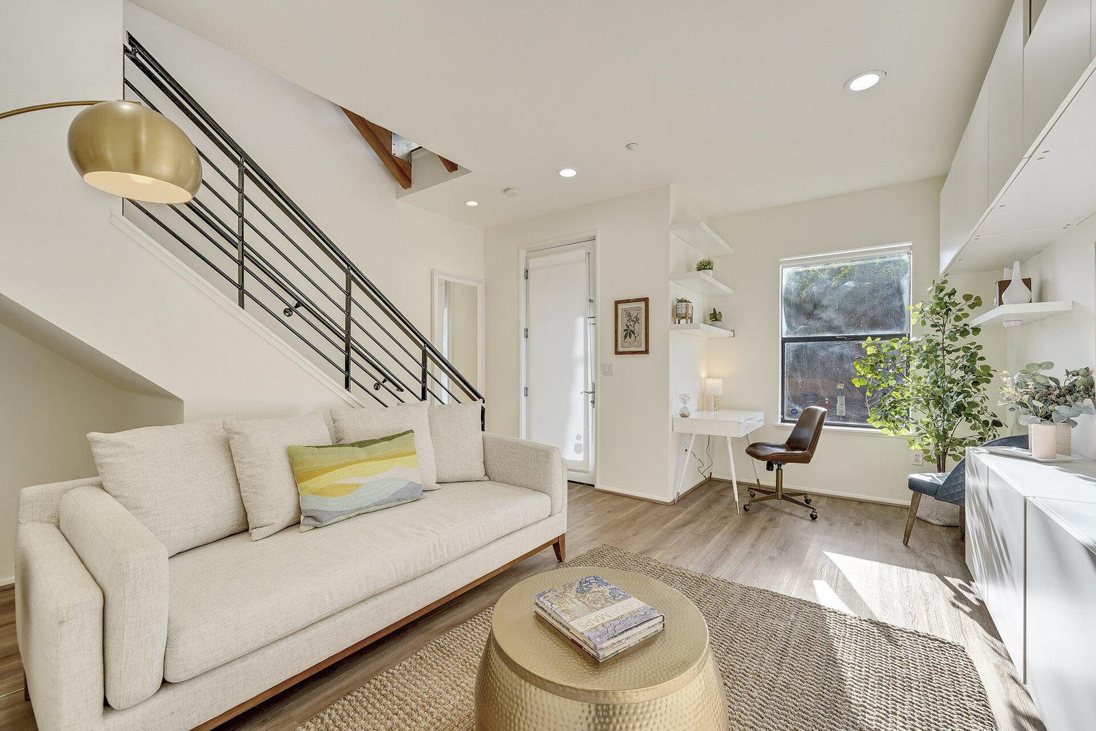 Entry/office area with a white desk, a leather office chair, and a view of a staircase with black railings.