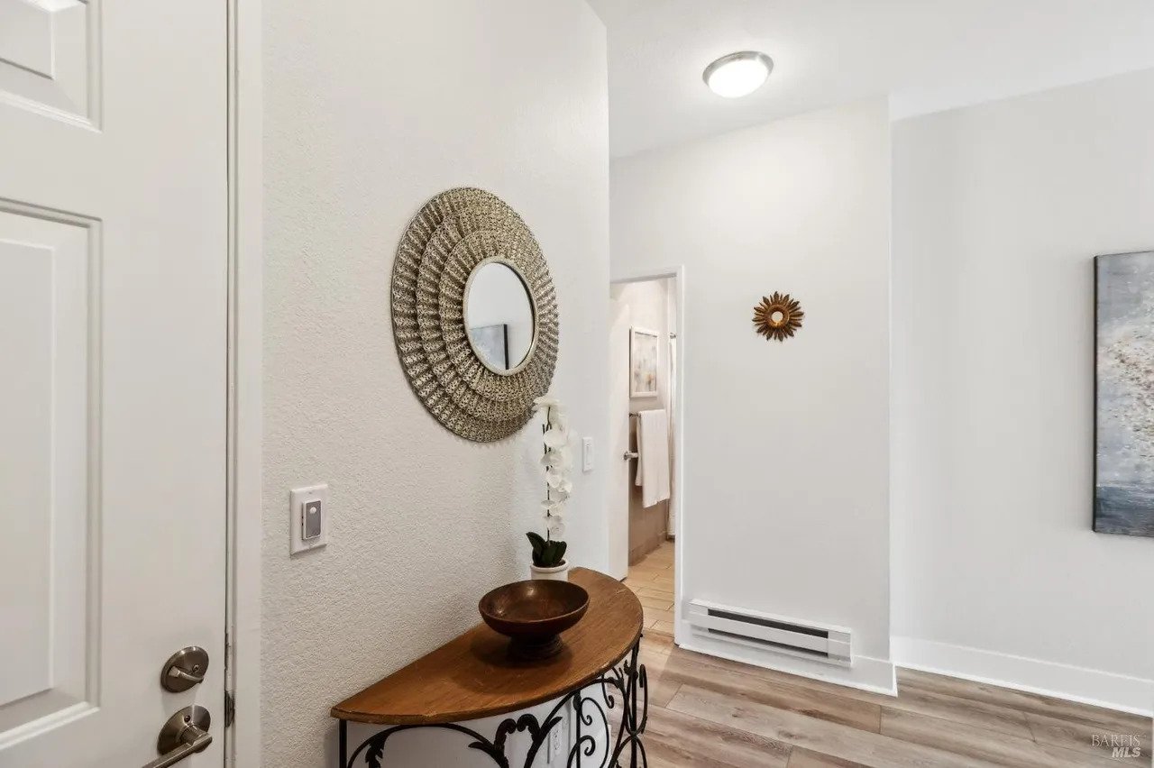 Entryway with a half-moon wooden console table, a decorative sunburst mirror, and a view into a hallway.